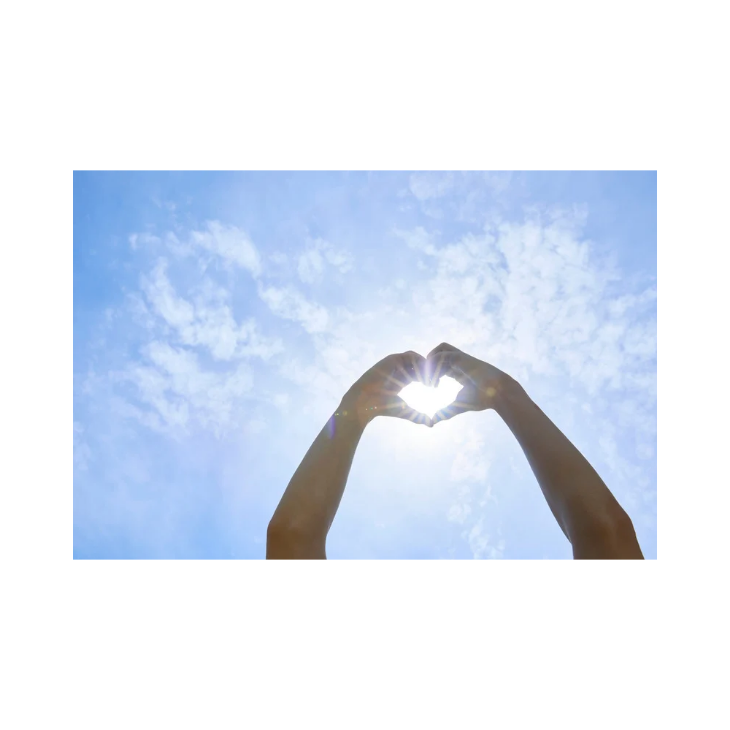空に向かってハートを作るカップルの画像