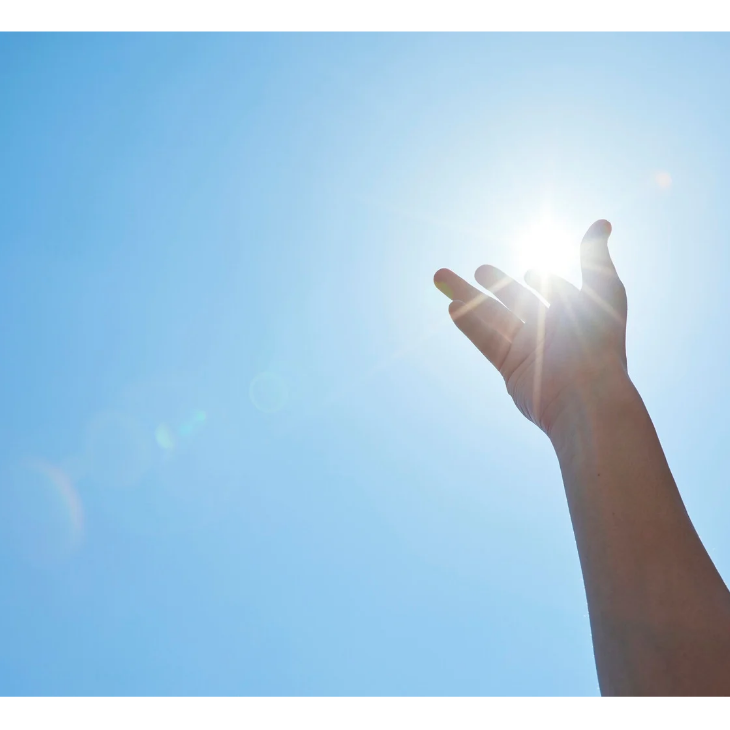 太陽に手をかざしている人。スピリチュアルなイメージ画像。